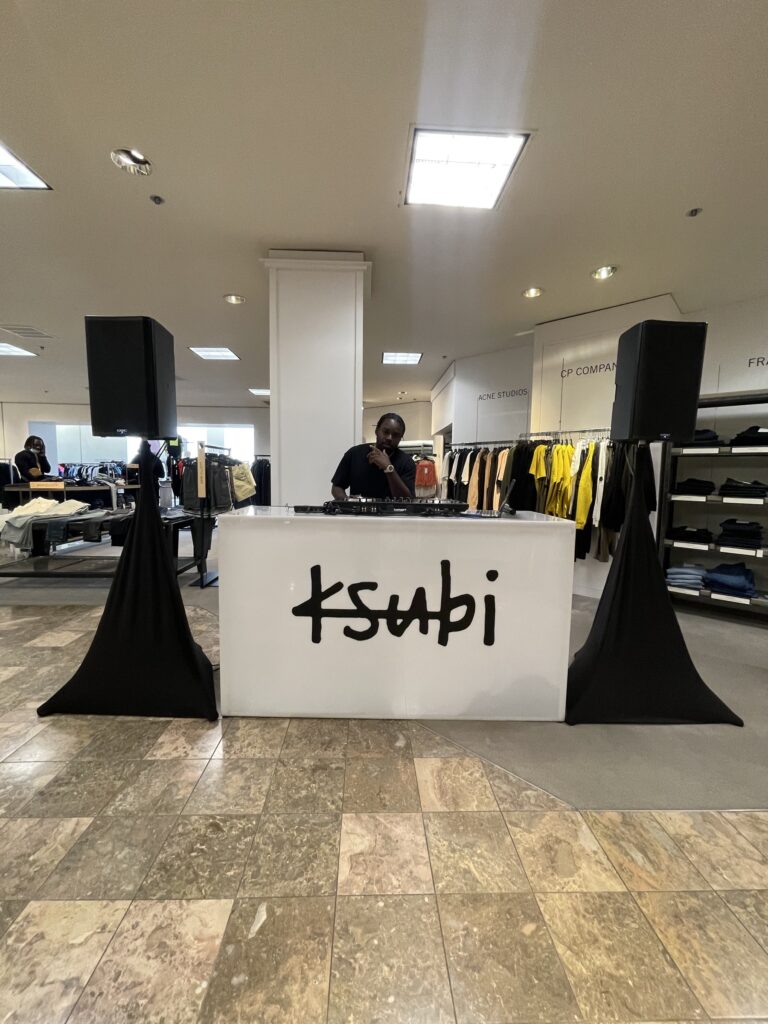 DJ A-Tron behind the Ksubi-branded DJ booth on the menswear floor of Neiman Marcus Beverly Hills, February 12, 2022