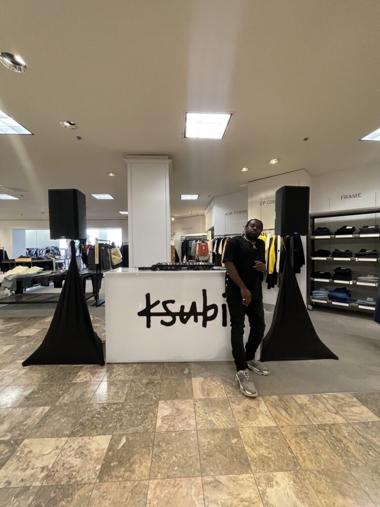 DJ A-Tron standing beside the Ksubi DJ booth inside Neiman Marcus Beverly Hills, February 12, 2022