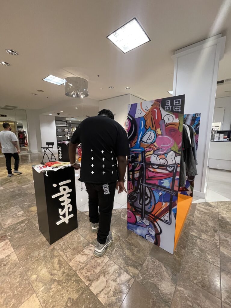 DJ A-Tron at the Ksubi pop-up display with its graffiti art panel inside Neiman Marcus Beverly Hills, February 12, 2022